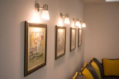 a row of pictures hanging on a wall with lights at Free.three in Belgrade