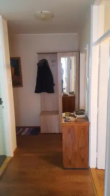 a room with a wooden table and a door with a coat hanging at Apartman Jogi in Vračar (historical)