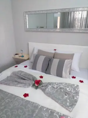 a white bed with red flowers on top of it at Apartman Fenix in Belgrade