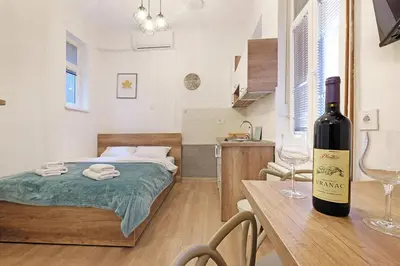 a room with a bed and a bottle of wine on a table at Ikar Apartments in Belgrade