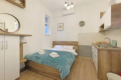a small bedroom with a bed and a sink at Ikar Apartments in Belgrade