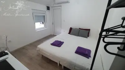 a bedroom with a white bed with purple pillows on it at Molders Apartments in Belgrade