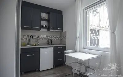 a kitchen with black cabinets and a sink and a window at Molders Apartments in Belgrade