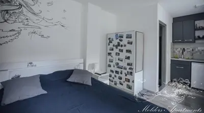 a bedroom with a bed and a refrigerator with pictures on the wall at Molders Apartments in Belgrade