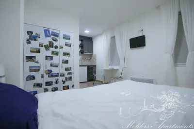 a bedroom with a white bed and a wall with pictures at Molders Apartments in Belgrade