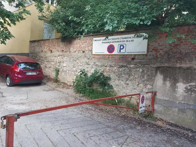 a red car parked next to a brick wall with a sign at Jumi in Belgrade