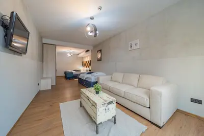 a living room with a white couch and a tv at Hotel Garni VIZURA Sport in Belgrade