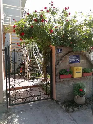 an open gate with red flowers and plants on it at Gardos riverview in Belgrade