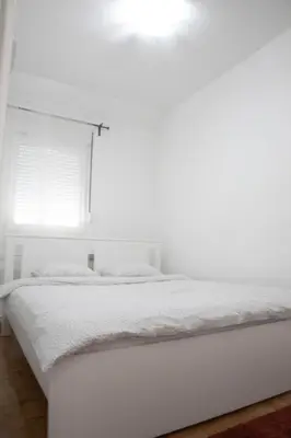 a white bed in a white bedroom with a window at Apartment Nikola Tesla in Belgrade