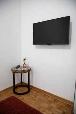 a room with a table and a flat screen tv on a wall at Apartment Nikola Tesla in Belgrade