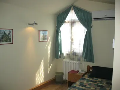 a bedroom with a window with a green curtain at Hostel Oasis in Belgrade