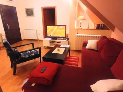 a living room with a red couch and a tv at Talas apartmani in Belgrade