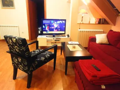 a living room with a tv and a chair and a table at Talas apartmani in Belgrade