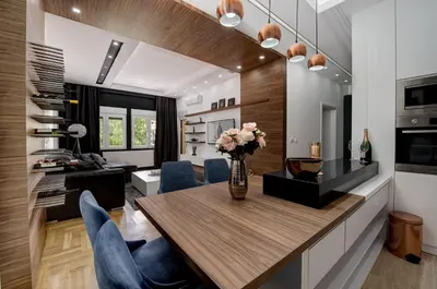 a kitchen and dining room with a table and blue chairs at CENTAR President in Arandjelovac