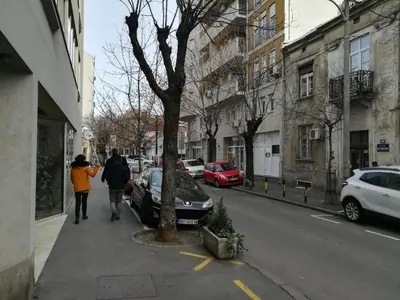 two people walking down a sidewalk next to a tree at Belgrade Center Apartment Skadarlija II in Belgrade