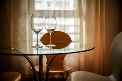 two wine glasses on a glass table in front of a window at Apartman Metropol Belville in Belgrade