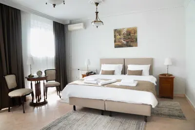 a bedroom with a large white bed and a chair at Hotel Jardin in Belgrade
