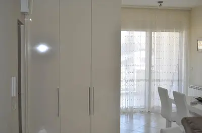 a white cabinet in a room with a table and chairs at Apartments Soleado in Pančevo
