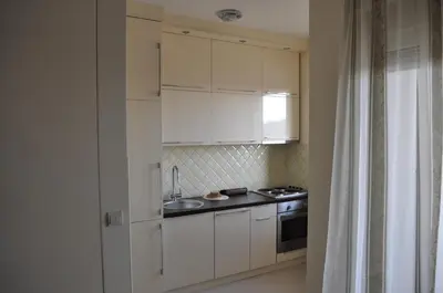 a kitchen with white cabinets and a sink and a stove at Apartments Soleado in Pančevo