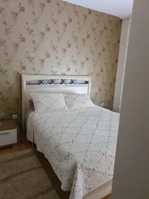 a small bedroom with a bed with a white comforter at Apartments Soleado in Pančevo