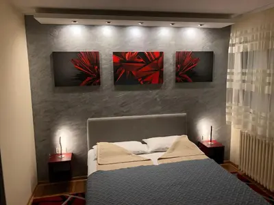 a bedroom with a bed with four paintings on the wall at Burgundy Apartment in Belgrade