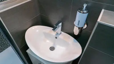 a bathroom with a white sink and a soap dispenser at Burgundy Apartment in Belgrade