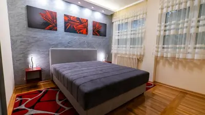 a bedroom with a bed and two paintings on the wall at Burgundy Apartment in Belgrade