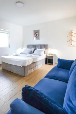 a bedroom with a bed and two blue couches at Airport Stay Apartments in Surčin