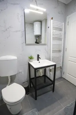a bathroom with a white toilet and a sink at Airport Stay Apartments in Surčin