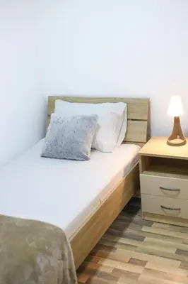 a bed with two pillows and a night stand with a lamp at Airport Stay Apartments in Surčin