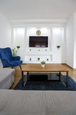 a living room with a coffee table and a blue chair at Airport Stay Apartments in Surčin