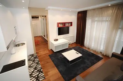 a living room with a white table and a tv at STATUS Superior Apartments in Belgrade