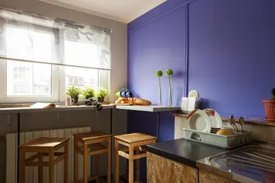 a kitchen with purple walls and wooden stools at Hostel Bed&Coffee 360° in Belgrade