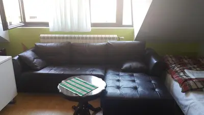 a black leather couch in a living room with a table at Guest House Boska in Pančevo