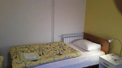 a small bedroom with a bed with a yellow comforter at Guest House Boska in Pančevo