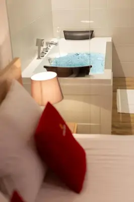 a bathroom with a sink and a bed with red pillows at Royal Suites in Belgrade