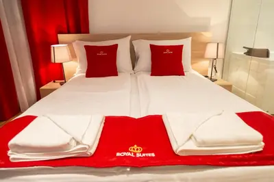 a large bed with red and white sheets and pillows at Royal Suites in Belgrade