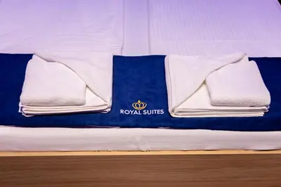 a bed with a blue and white blanket and towels at Royal Suites in Belgrade