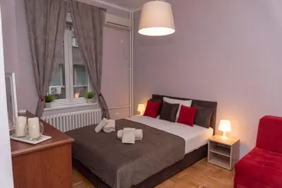 a bedroom with a bed and a red chair at Sweet House Trg in Belgrade