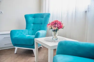 a vase of flowers on a table next to two chairs at Drop In Apartments in Belgrade