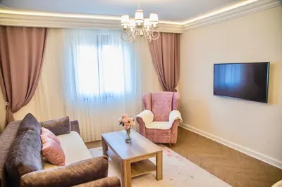 a living room with a couch and chairs and a tv at Drop In Apartments in Belgrade
