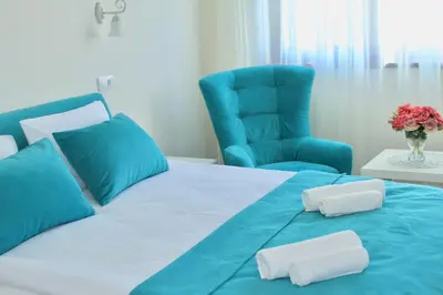 a blue bed with two pillows and a blue chair at Drop In Apartments in Belgrade