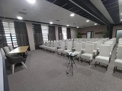 a conference room with white chairs and a table at Garnet Hotel & Event Centar in Ruma