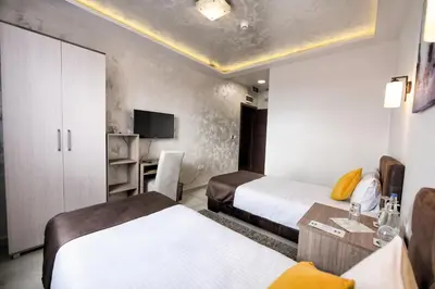 a hotel room with two beds and a tv at Garnet Hotel & Event Centar in Ruma