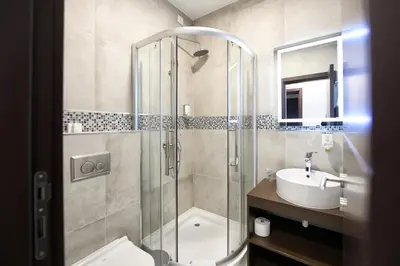 a bathroom with a shower and a toilet and a sink at Garnet Hotel & Event Centar in Ruma