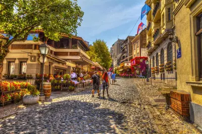 two people walking down a cobblestone street in a city at City Center Belgrade Cozy Apartment Skadarlija in Belgrade