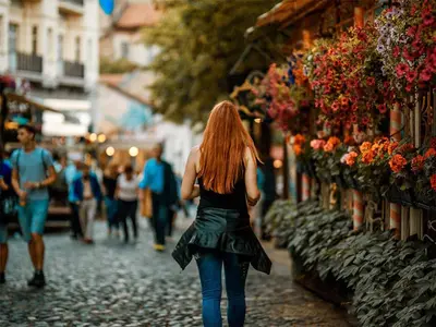 a woman walking down a street in a city at City Center Belgrade Cozy Apartment Skadarlija in Belgrade