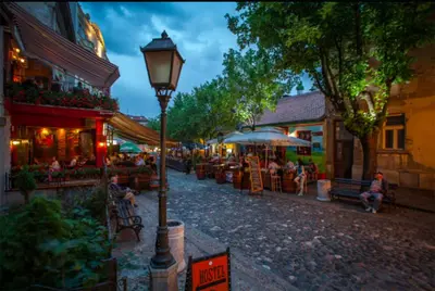 a street with a street light and people sitting at tables at City Center Belgrade Cozy Apartment Skadarlija in Belgrade