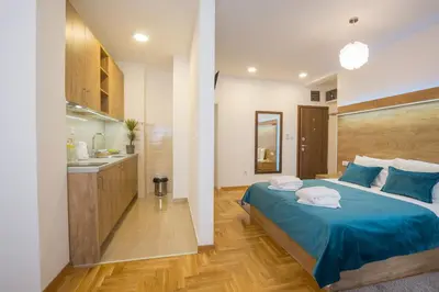 a bedroom with a blue bed and a kitchen at Thomas Residence in Belgrade