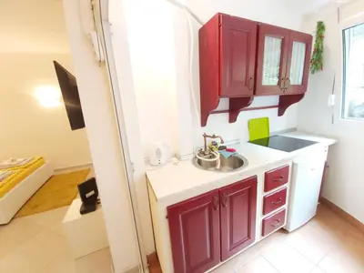 a small kitchen with a sink and red cabinets at White Pearl in Belgrade